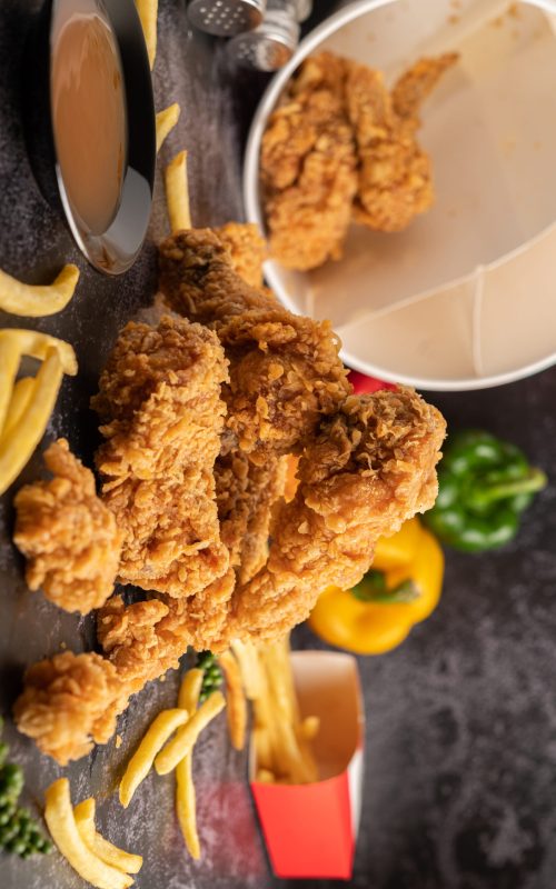 Fried Chicken and French Fries on Black Cement Floor.